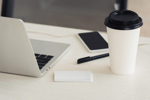 cartões de visita vazios brancos, laptop, café para ir, caneta e smartphone com tela em branco na mesa de escritório
 - Foto, Imagem