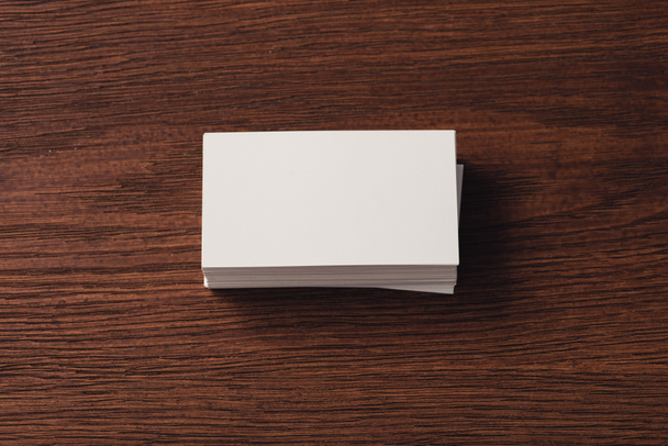 kahverengi ahşap yüzey üzerinde yığılmış beyaz kartvizit üst görünümü - Fotoğraf, Görsel