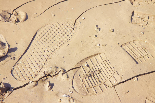 Empreinte lourde laissée sur un sable boueux par une botte mâle
 - Photo, image