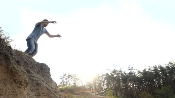Man springt in een zand in slow motion buitenshuis bij zonsondergang. - Video