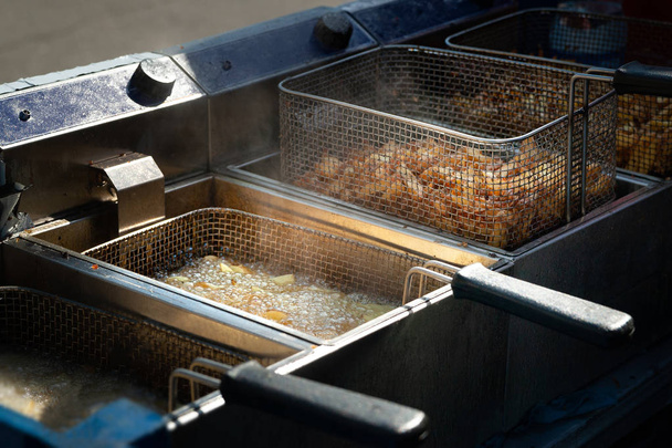 Smażone ziemniaki. Frytki smażone we wrzącej oleju w Frytownice.  - Zdjęcie, obraz