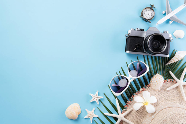 Beach accessories retro film camera, sunglasses, airplane, starfish beach hat and sea shell on blue pastel background for summer holiday and vacation concept. - Fotó, kép