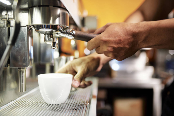 Zbliżenie męskich rąk oddanie filiżankę pod żurawia ekspresu do kawy i podejmowania gorącej kawy dla klienta w kawiarni - Zdjęcie, obraz