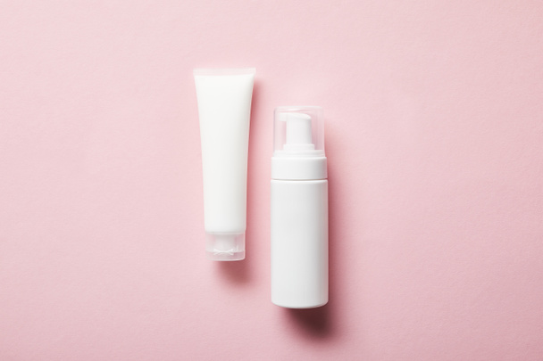 top view of cream tube with hand cream and cosmetic dispenser on pink  - Fotó, kép