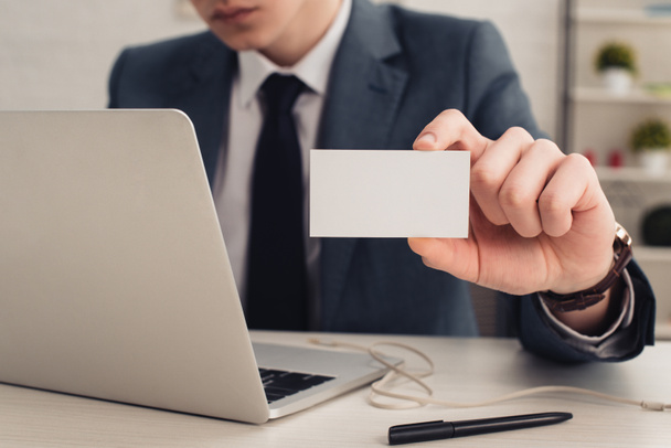 partial view of businessman holding white business card while using laptop - Fotografie, Obrázek