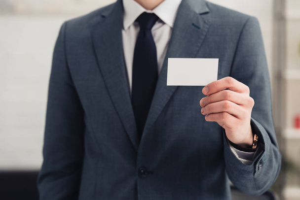 cropped view of businessman in formal wear holding blank business card - Valokuva, kuva
