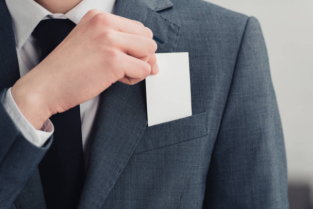 空白の名刺を持つスーツを着たビジネスマンのトリミングされたビュー - 写真・画像