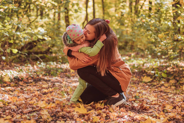 Мама и дочь в осеннем парке играют, обнимаются и радуются
 - Фото, изображение