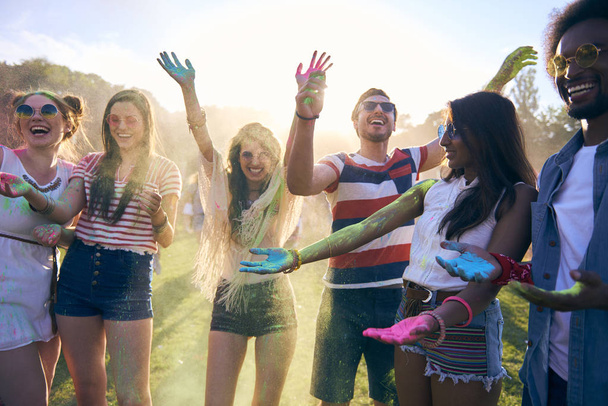 Φίλοι διασκεδάζουν κατά τη διάρκεια του φεστιβάλ μουσικής με σκόνες χρώματος - Φωτογραφία, εικόνα