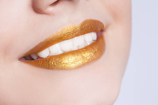 Beautiful closeup female lips with gold color makeup - Photo, Image