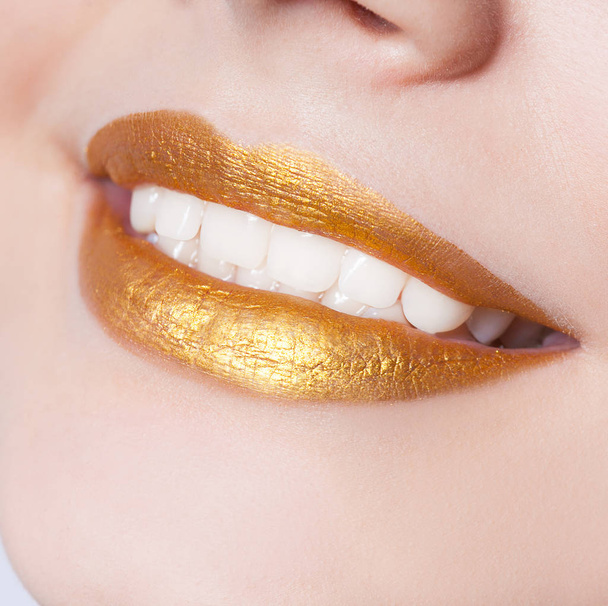 Beautiful closeup female lips with gold color makeup - Photo, image