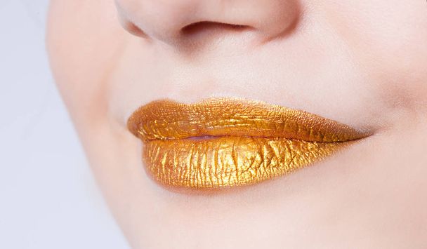 Beautiful closeup female lips with gold color makeup - Fotoğraf, Görsel