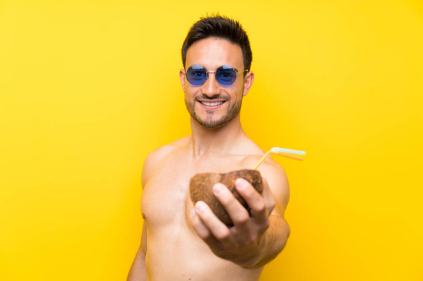 Komea nuori mies kesävaatteissa cocktailin kanssa kookospähkinässä
 - Valokuva, kuva