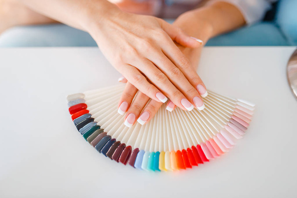 Female customer hands and colorful nail varnish palette in beauty shop. Professional manicure and pedicure service, hands and legs treatment, client in beautician salon, woman at the manicurist - Φωτογραφία, εικόνα