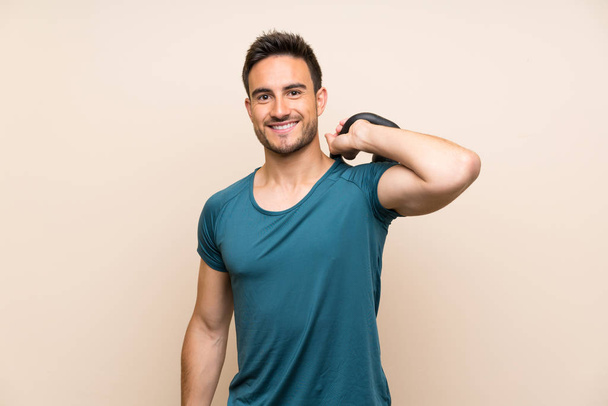 Handsome sport man over isolated background with kettlebell - Foto, afbeelding