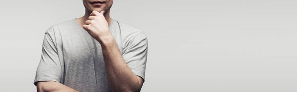 cropped view of man holding hand near face isolated on grey, panoramic shot, human emotion and expression concept - Foto, Bild