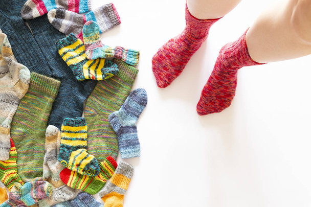 Meias de lã coloridas e um par de pernas no fundo branco
 - Foto, Imagem