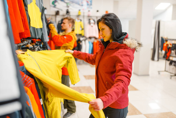 Woman at the showcase choosing skiing or snowboarding equipment, shopping in sports shop. Winter season extreme lifestyle, active leisure store, customer buying ski - 写真・画像