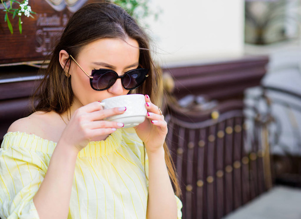 Woman in sunglasses drink coffee outdoors. Girl relax in cafe cappuccino cup. Caffeine dose. Coffee for energetic successful day. Waiting for date. Breakfast time in cafe. Girl enjoy morning coffee - Foto, Imagem