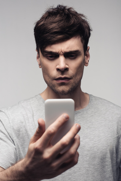 thoughtful, serious man having video chat on smartphone isolated on grey - 写真・画像