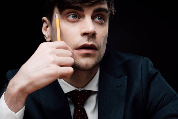 gondolkodó üzletember néz el, miközben megható arca ceruzával - Fotó, kép