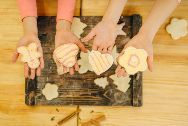 Дві маленькі дівчата готують руки тримають печиво над дерев'яною дошкою, готують пекарню на кухні, смішні пекарні. Дитяче кулінарне тістечко, дитячі кухарі готують торт
 - Фото, зображення