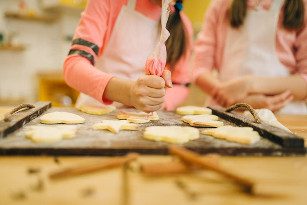 Dos niñas cocineras preparándose para enviar galletas al horno, preparación de panadería en la cocina, panaderos divertidos. Niños cocinando pastelería y divirtiéndose, niños chefs prepara pastel
 - Foto, Imagen