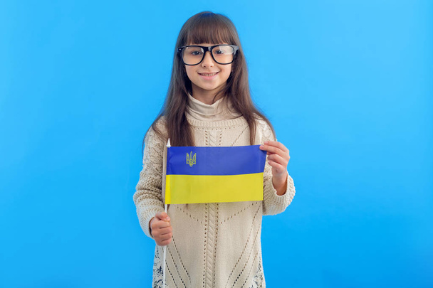 Little girl with the flag of Ukraine on a blue background. Schoolgirl studying abroad. - Foto, Imagem