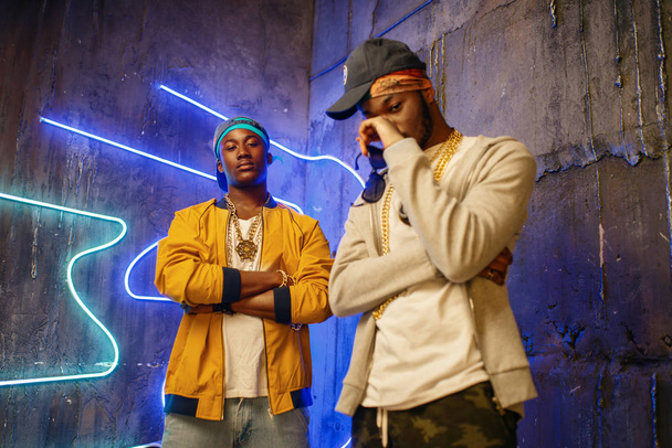 Two African rappers, perfomance in club with neon lights on background. Rap performers in subway, underground music concert, urban style - Zdjęcie, obraz
