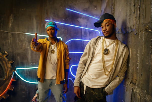 Two African rappers, perfomance in club with neon lights on background. Rap performers in subway, underground music concert, urban style - Photo, Image