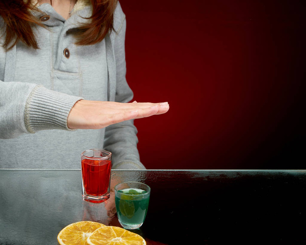 Refusal to offer to drink alcohol with ice in a transparent glass on a red background - Photo, Image