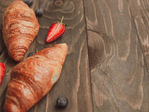 Primer plano desayuno de verano con croissants y fresa sobre tablones de madera, espacio para copiar
 - Foto, imagen