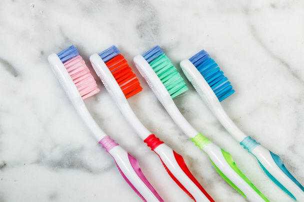 Vier plastic gekleurde tandenborstels op een marmeren tafel - Foto, afbeelding