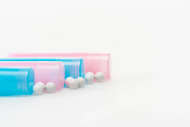 blue and pink bottles near round pills on white  - Foto, afbeelding