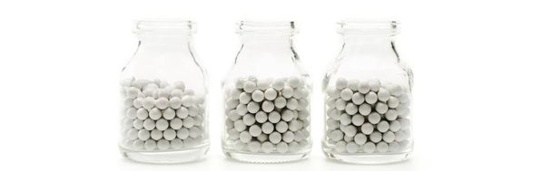 панорамный снимок стеклянных бутылок с круглыми таблетками, изолированными на белом
  - Фото, изображение