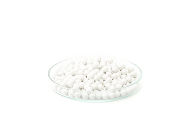okrągłe małe pigułki w szklanej szalce Petriego na białym tle  - Zdjęcie, obraz