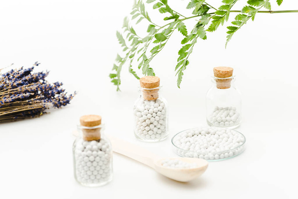 selective focus of medicine in glass bottles with wooden corks near green leaves on white  - 写真・画像