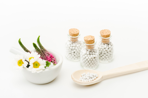 flowers in mortar near pestle and glass bottles with pills on white  - Photo, Image