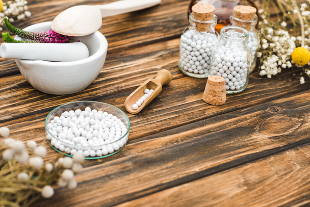 selective focus of bottles with pills near mortar with veronica flowers on wooden table  - Photo, Image