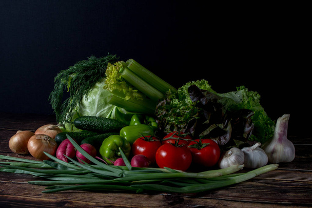 set of fresh vegetables in the dark. vegetarian food on wooden background. vegetable harvest from the garden. - Photo, Image