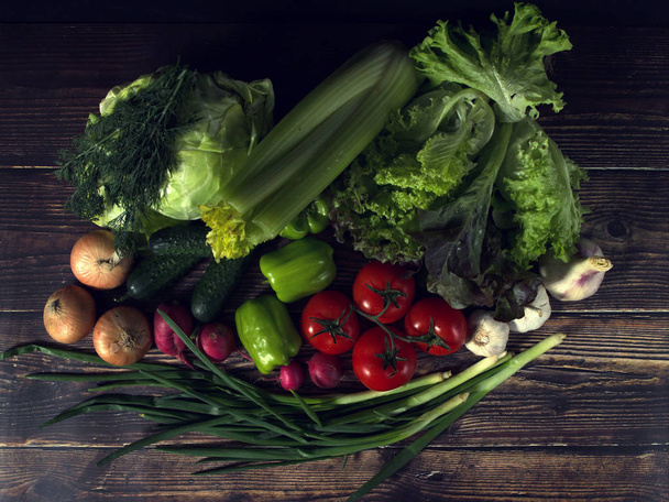 set of fresh vegetables in the dark. vegetarian food on wooden background. vegetable harvest from the garden. - Фото, зображення