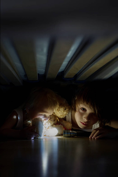 Μικρό παιδί, κρυμμένο κάτω από το κρεβάτι, αγκάλιασμα αρκούδων και ερασιτεχν - Φωτογραφία, εικόνα