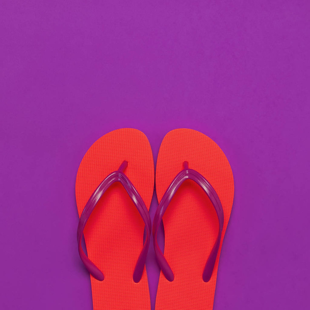 Coral flip flops on purple background. Flat lay, top view, copy space. Creative Summer Vacation travel Background. Women's summer footwear. Bright flip flops, trend colors - Photo, Image