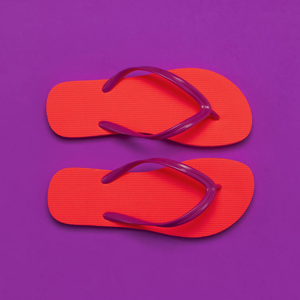 Coral flip flops on purple background. Flat lay, top view, copy space. Creative Summer Vacation travel Background. Women's summer footwear. Bright flip flops, trend colors - Photo, Image