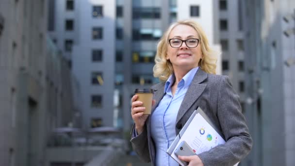 Female corporate worker breathing free holding coffee cup and work documents - Séquence, vidéo