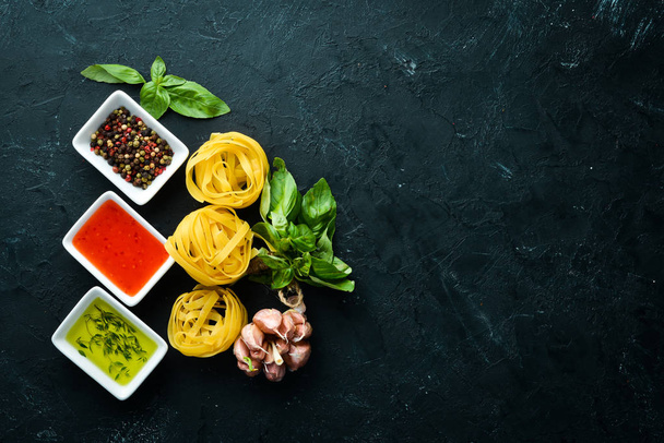 Dry pasta, sauces and spices. On a black background. Top view. Free space for your text. - 写真・画像