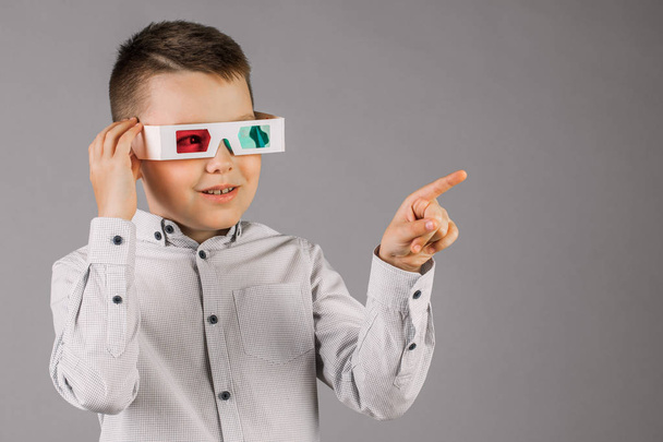 junger hübscher Junge mit 3D-Brille auf grauem Hintergrund im Studio. - Foto, Bild