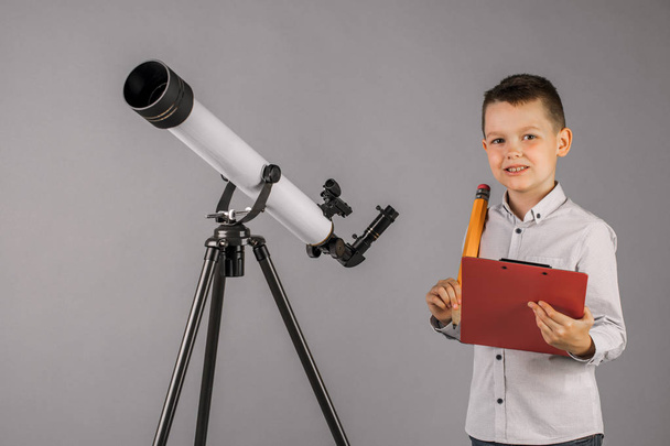 junger Astronom blickt durch ein Teleskop und schreibt in die Registerkarte - Foto, Bild