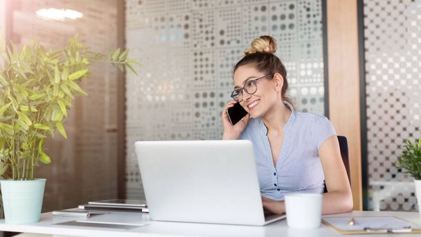 Young business woman working on laptop in office - Photo, image