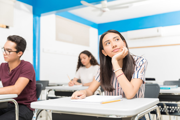 Pensativo adolescente sentado con compañeros de clase durante la conferencia en la escuela secundaria
 - Foto, Imagen